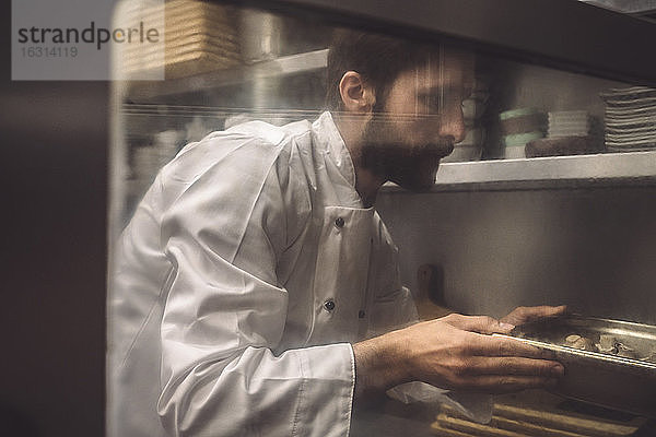 Männlicher Chefkoch backt Pilze in Großküche