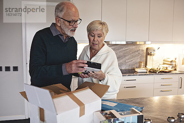 Älteres Ehepaar packt Paket über Kücheninsel zu Hause aus