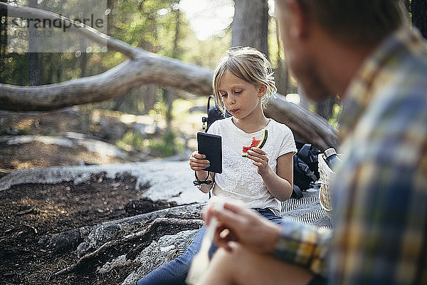 Tochter isst Wassermelone und telefoniert mit ihrem Vater im Wald