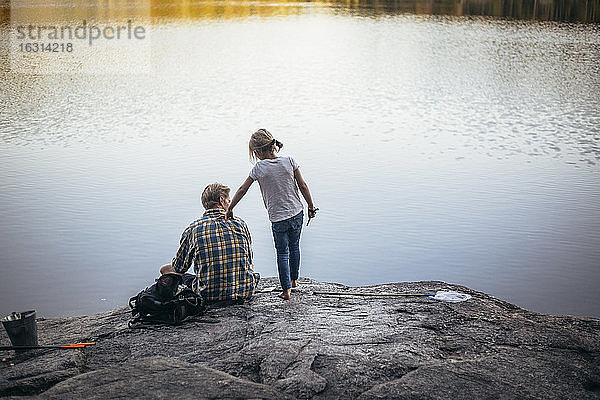 Rückansicht von Vater und Tochter beim Angeln am See
