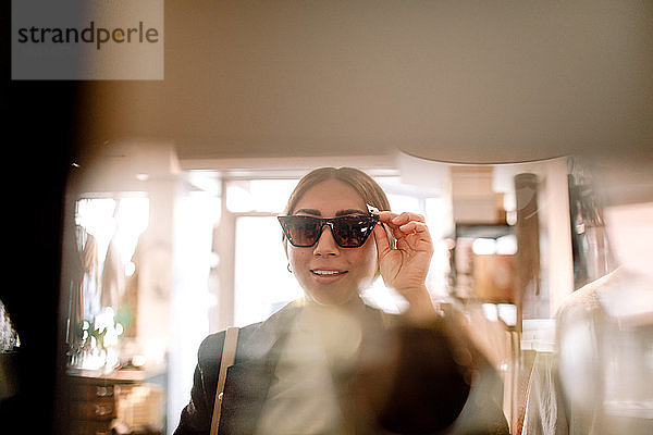 Junge Frau probiert Sonnenbrille im Modegeschäft aus