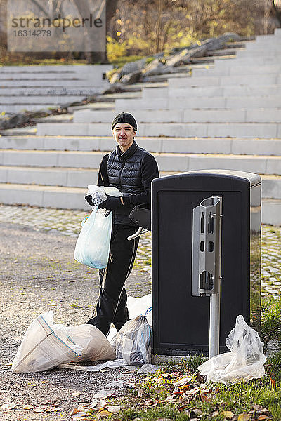Porträt eines Umweltschützers mit Plastikmüll an der Mülltonne