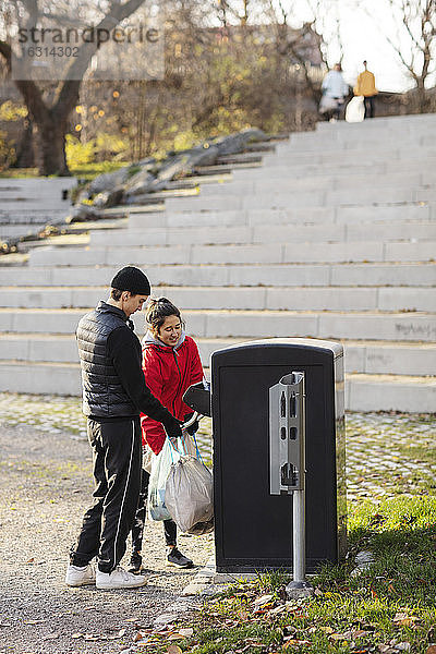 Männliche und weibliche Freiwillige  die Plastik in den Mülleimer werfen
