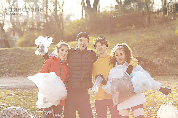 Lächelnde männliche und weibliche Umweltschützer mit Mikroplastikmüll im Park stehend