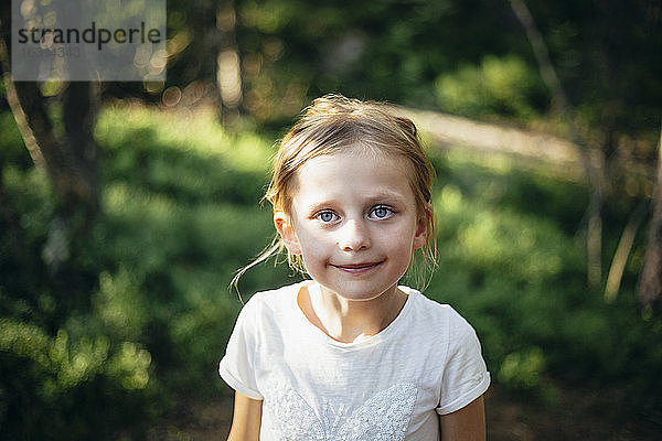 Porträt eines lächelnden Mädchens im Wald stehend