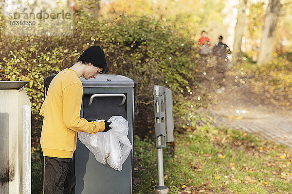 Männlicher Freiwilliger wirft Plastikmüll in den Mülleimer