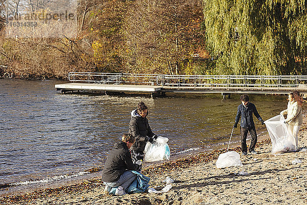 Männliche und weibliche Freunde sammeln Plastikmüll am See