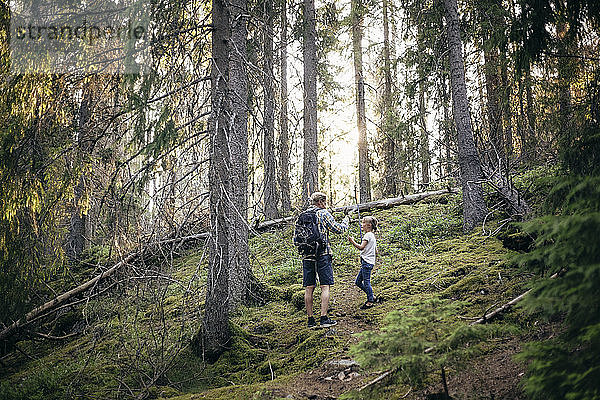 Vater mit Rucksack spricht mit Tochter im Wald