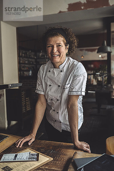 Porträt eines lächelnden reifen Kochs im Restaurant stehend