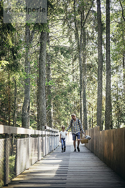 Vater spricht mit Tochter beim Spaziergang auf Steg im Wald