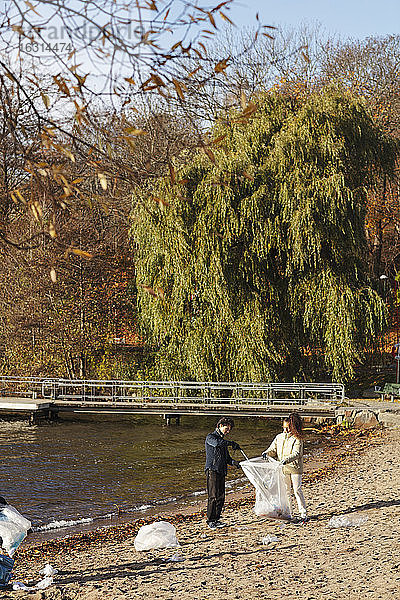 Freunde und Freundinnen beim Müllsammeln am See