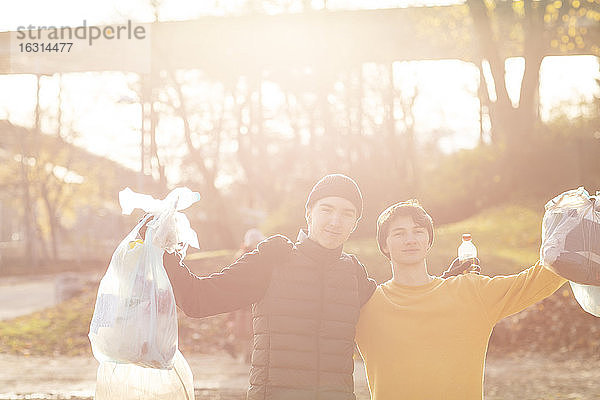 Porträt junger männlicher Freiwilliger mit Plastikmüll im öffentlichen Park stehend