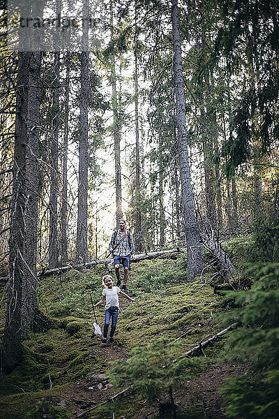 Lächelnde Tochter und Vater gehen im Wald spazieren