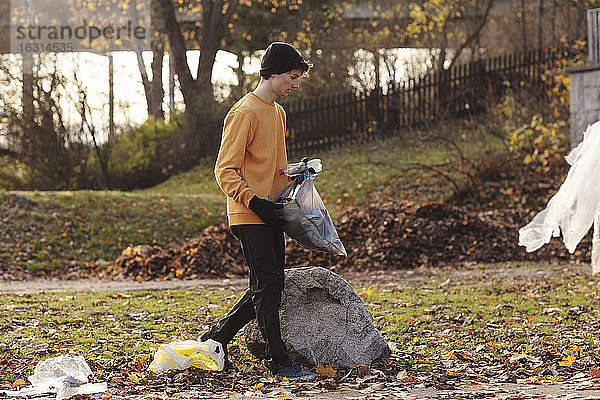 Männlicher Freiwilliger  der beim Spaziergang im Park Müll sammelt