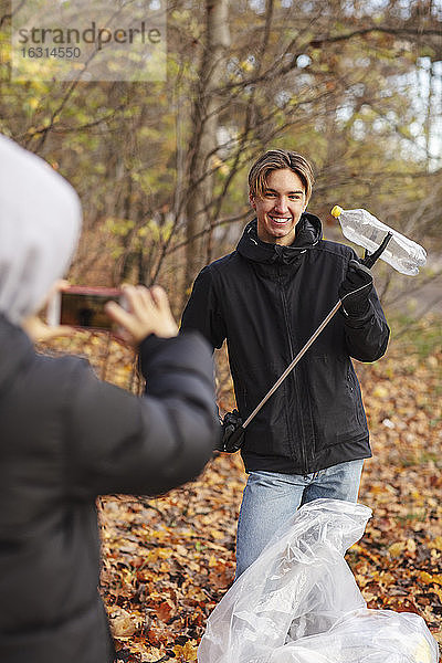 Teenager fotografiert im Herbst einen Freund mit einer Plastikflasche im Park