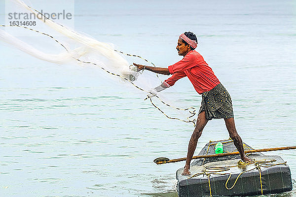 Fischer werfen ein beschwertes Netz auf ein kleines Floß vor dem beliebten Marari-Strand  Mararikulam  Alappuzha (Alleppey)  Kerala  Indien  Asien