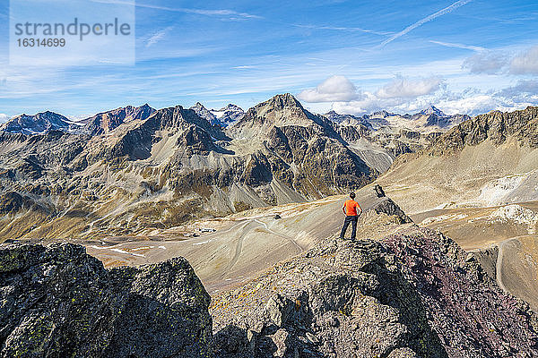 Rückansicht des Mannes auf dem Gipfel des Piz Nair mit Blick auf den Piz Suvretta  Engadin  Kanton Graubünden  Schweiz  Europa