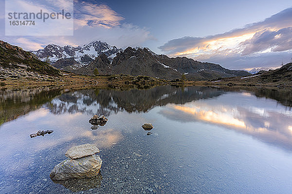 Sonnenaufgang beleuchtete den felsigen Gipfel des Monte Disgrazia  der sich im klaren Wasser des Zana-Sees spiegelte  Valmalenco  Valtellina  Lombardei  Italien  Europa