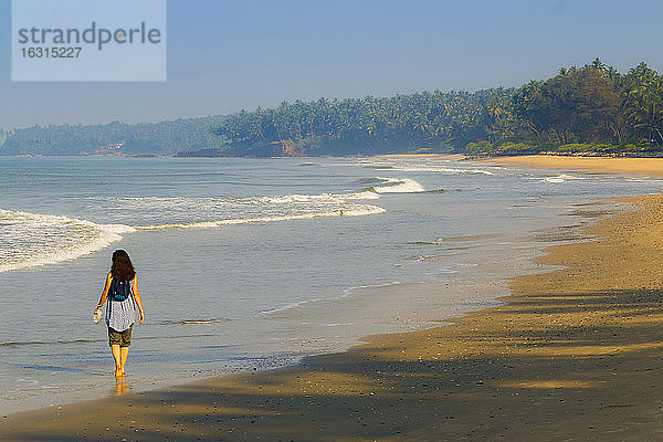Einsamer Reisender am wunderschönen palmengesäumten Strand von Kizhunna  südlich von Kannur an der Nordküste Keralas  Kizhunna  Kannur  Kerala  Indien  Asien