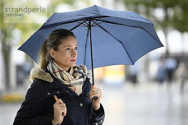Frau mit in winterlicher Kleidung mit Regenschirm  Portrait  Stuttgart  Baden-Württemberg  Deutschland  Europa