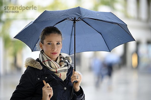 Frau mit in winterlicher Kleidung mit Regenschirm  Portrait  Stuttgart  Baden-Württemberg  Deutschland  Europa