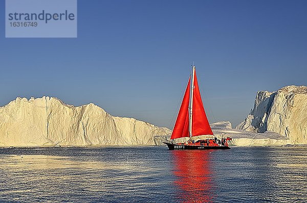 Rotes Segelboot vor Eisbergen  Eisfjord  UNESCO-Weltnaturerbe  Diskobucht  Ilulissat  Westgrönland  Grönland  Nordamerika