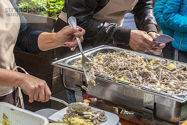 Menschen  die die traditionellen Pizzoccheri während eines Essensfestes im Freien servieren  Veltlin  Provinz Sondrio  Lombardei  Italien  Europa