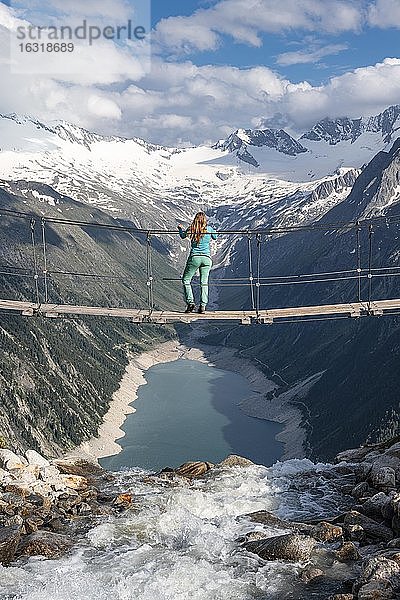 Wanderin  Frau auf Hängebrücke an der Olpererhütte  Schlegeisstausee  Speicher Schlegeis  Zillertaler Alpen  Gletscher Schlegeiskees  Zillertal  Tirol  Österreich  Europa