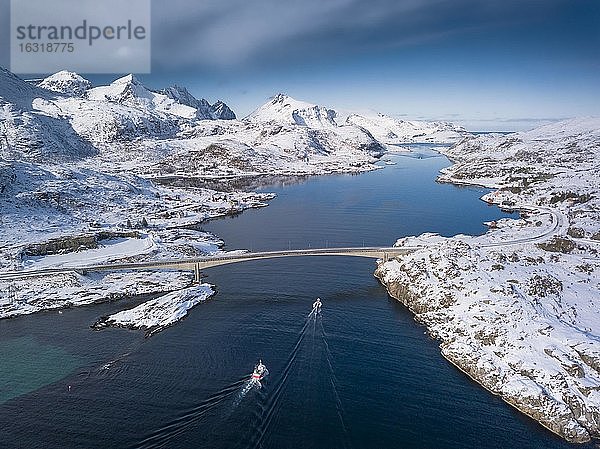 Luftaufnahme  Fjord Meeresstraße mit verschneiten Bergen  Brücke mit Landstraße und kleine Fischerboote  Nordland  Lofoten  Norwegen  Europa