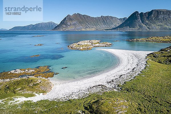 Halbmondförmige Bucht  weißer Sandstrand  türkises Meer  vorne Küste grasbewaschsen  hinten steile Berge  Vågan  Lofoten  Nordland  Norwegen  Europa