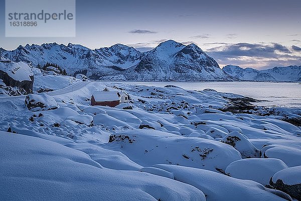 Tief verschneite Winterlandschaft am Meer  Holzhütte an Küste  hinten Berge  Nordland  Lofoten  Norwegen  Europa