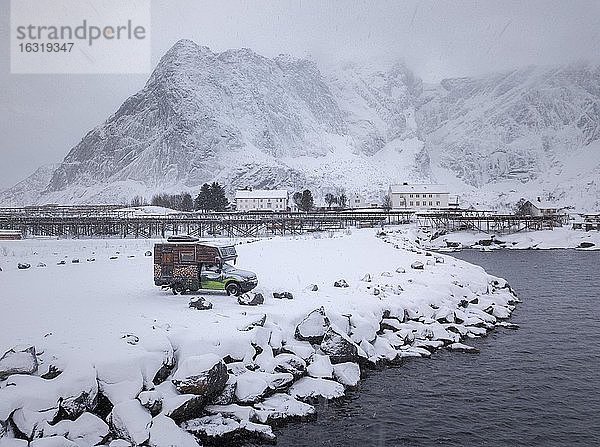 Wohnmobil bemalt als Almhütte bei Schneefall am Parkplatz vor einem Fjord  Reine  Nordland  Lofoten  Norwegen  Europa