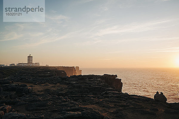 Leuchtturm auf den Klippen mit Blick auf eine ruhige Meereslandschaft bei Sonnenuntergang  Peniche  Portugal