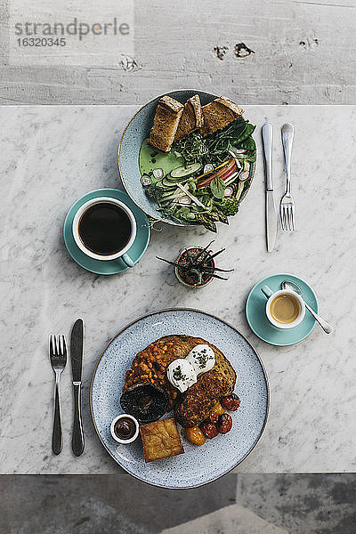 Komplettes englisches Frühstück und Grünzeug auf Toast auf dem Tisch des Restaurants