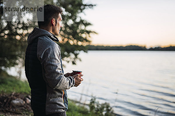 Mann schaut auf den See  trinkt Kaffee
