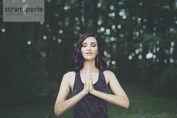 Junge Frau meditiert mit geschlossenen Augen im Wald  Yoga in der Natur