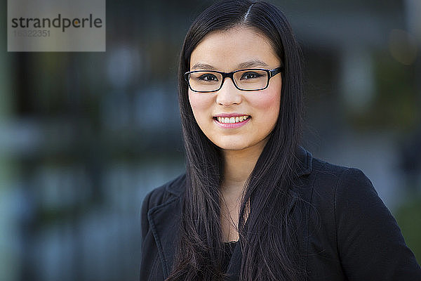 Porträt einer lächelnden jungen Geschäftsfrau mit Brille