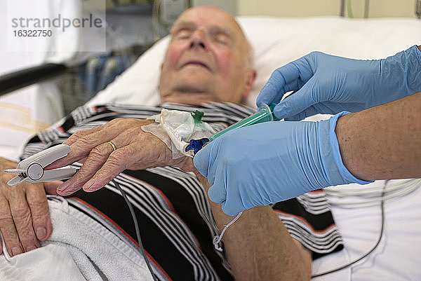 Entnahme einer Blutprobe bei einem älteren Mann  der nach einem Herzinfarkt auf der Intensivstation liegt