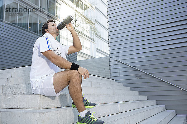 Sportler macht eine Pause und trinkt aus seiner Flasche