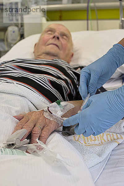 Entnahme einer Blutprobe bei einem älteren Mann  der nach einem Herzinfarkt auf der Intensivstation liegt
