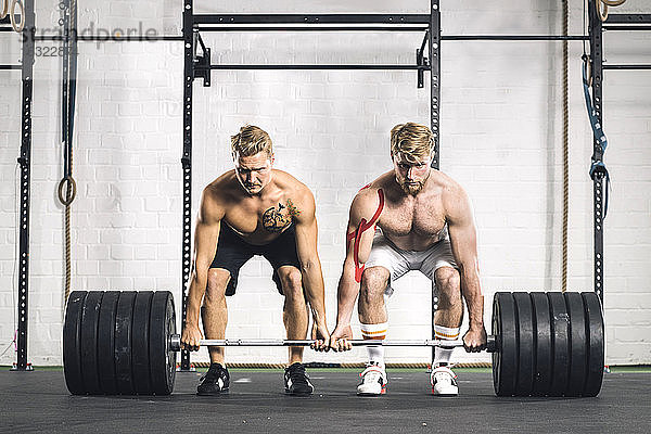 Zwei junge Männer im Fitnessstudio heben Gewichte