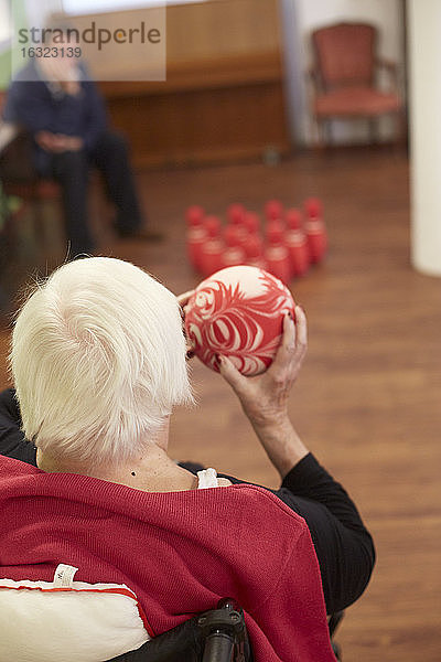 Altersdemente Seniorin beim Bowling mit Schaumstoffball in einem Pflegeheim