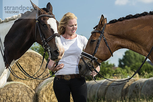 Deutschland  Wiesenau  blonde Frau mit zwei Pferden