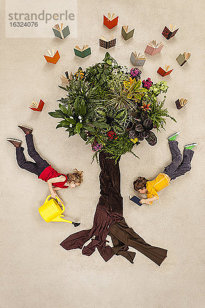 Junge und Mädchen gießen einen Bücherbaum