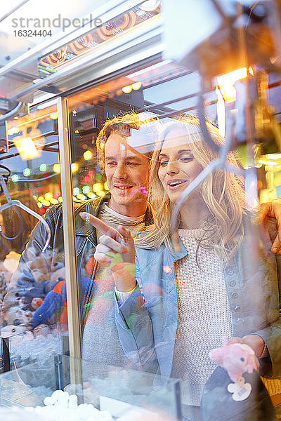 Junges Paar auf dem Jahrmarkt betrachtet die Preise im Fenster