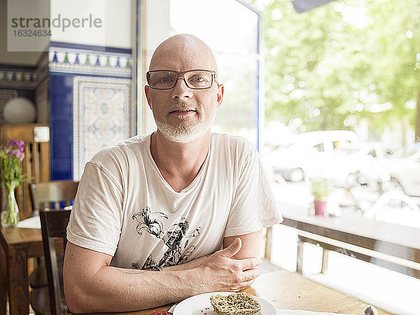 Deutschland  Berlin  Älterer Mann sitzt im Café und schaut in die Kamera