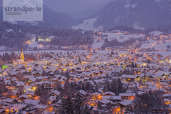 Deutschland  Bayern  Blick auf das schneebedeckte  beleuchtete Oberstdorf in der Dämmerung vor den Allgäuer Alpen