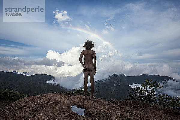 Sri Lanka  Horton Plains National Park  Rückansicht eines nackten Mannes auf einem Aussichtspunkt  Regenbogen