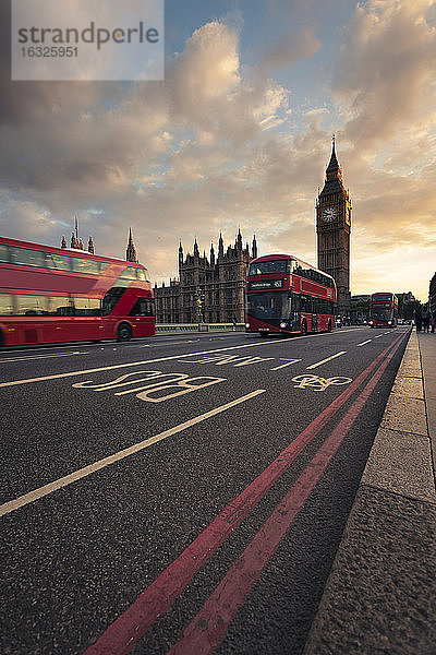 Großbritannien  London  rote Busse fahren an der Westminster Bridge vorbei  im Hintergrund der Turm Big Ben bei Sonnenuntergang