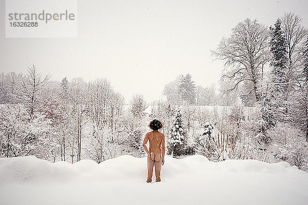 Rückansicht eines nackten Mannes  der im Schnee steht
